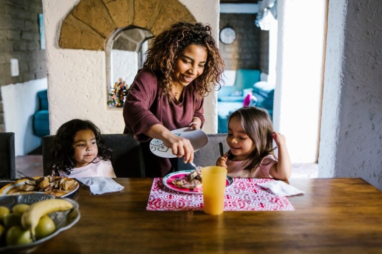 mother serving breakfast to her daughters at home in Latin America